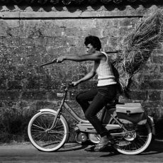 A vélomoteur, la jeune agricultrice transporte une botte de paille